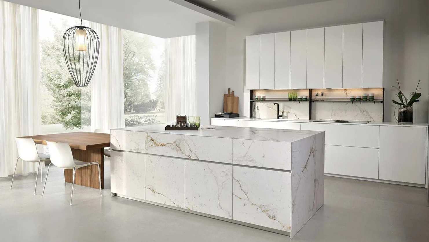 European kitchen with handleless white fronts, a marble-clad island, ceiling-height wall units and an integrated hob