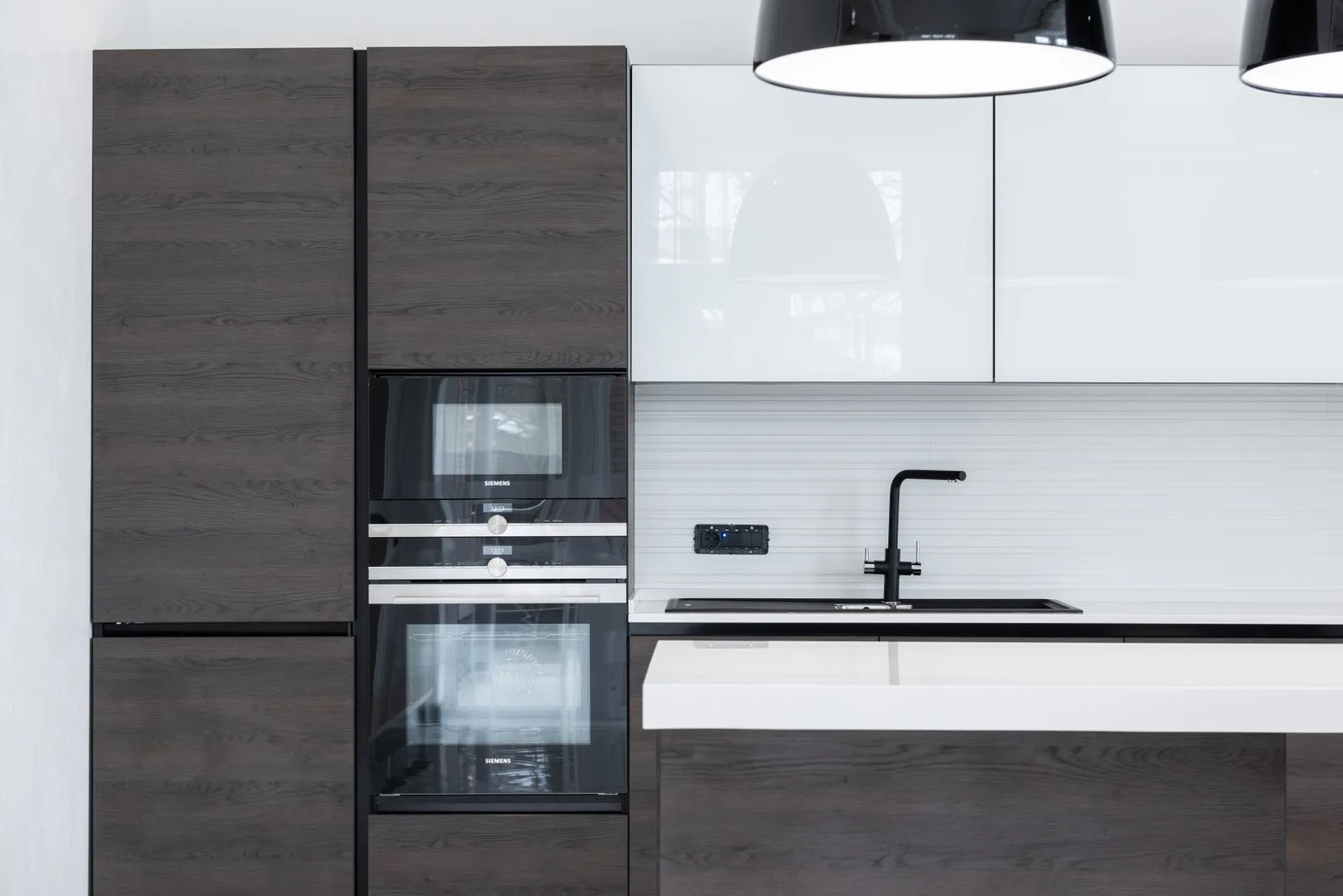 Modular kitchen with tall units, a stone counter and under-cabinet task lighting