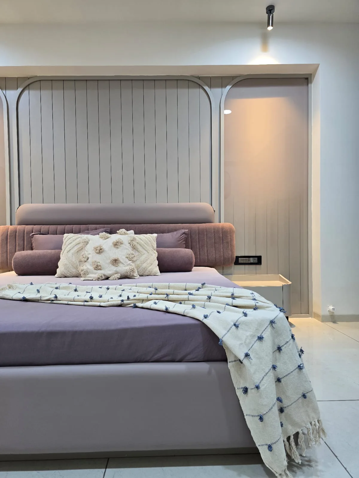 Bedroom with a fluted panel headboard, soft bedside lighting and a full-height fitted wardrobe