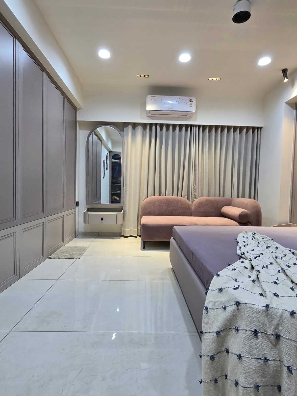Bedroom with completed wardrobe and lounge seating, surfaces protected until final handover