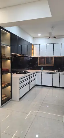 L-shaped modular kitchen in high-gloss black and white, from the same 4 BHK turnkey flat