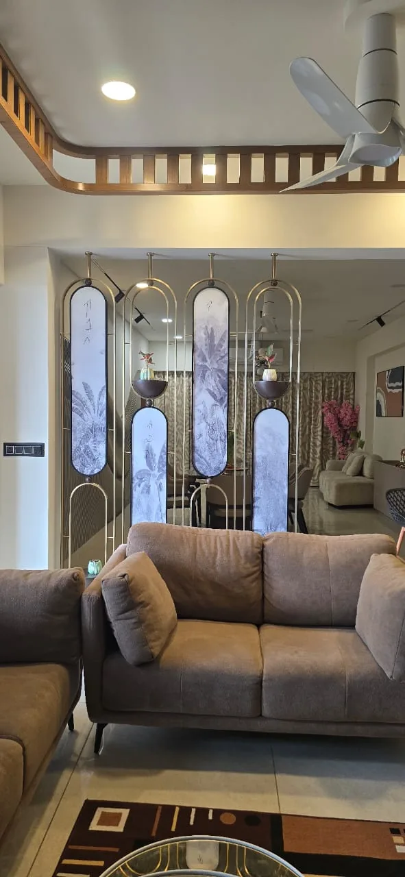 Living room divided from the dining area by brass-framed arched glass screens, from a 4 BHK turnkey flat in Ahmedabad