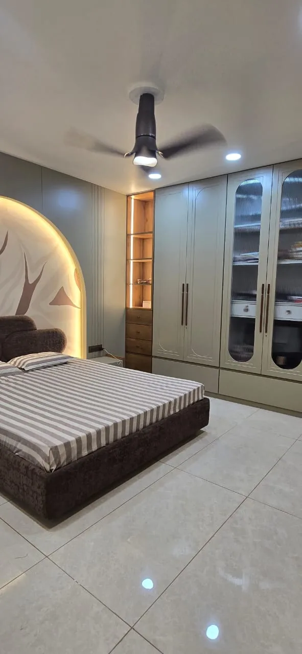 Master bedroom with sage-green wardrobes, fluted glass display fronts and a backlit arch headboard