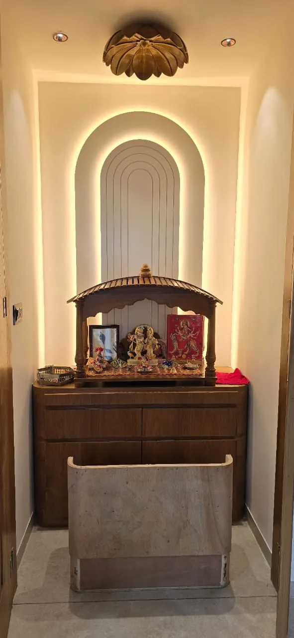 Pooja room with a concentric backlit arch niche, carved timber ceiling rose and a wooden temple